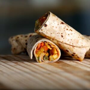 Delicious vegetarian wrap filled with colorful veggies on a wooden surface.